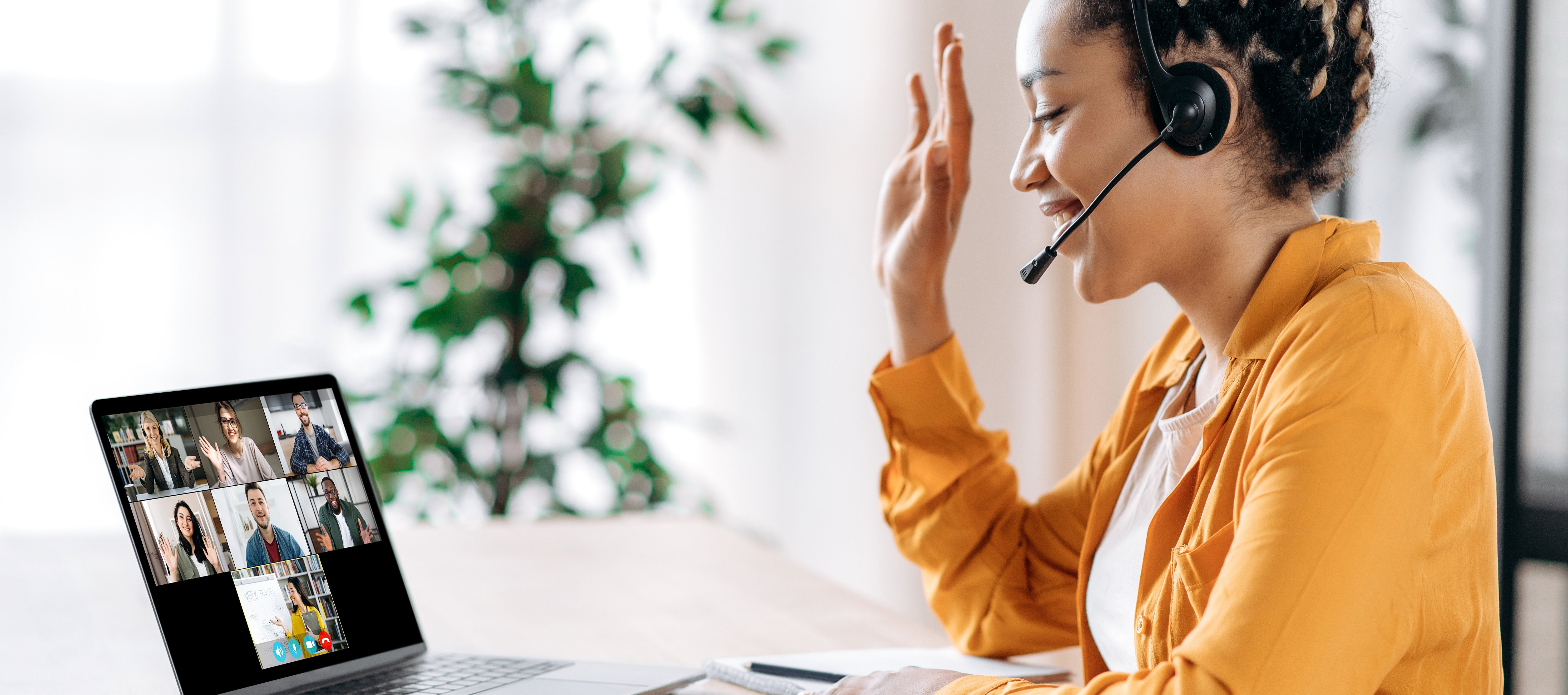 Junge Frau schaut auf Laptop, Hand erhoben, Webinarsituation