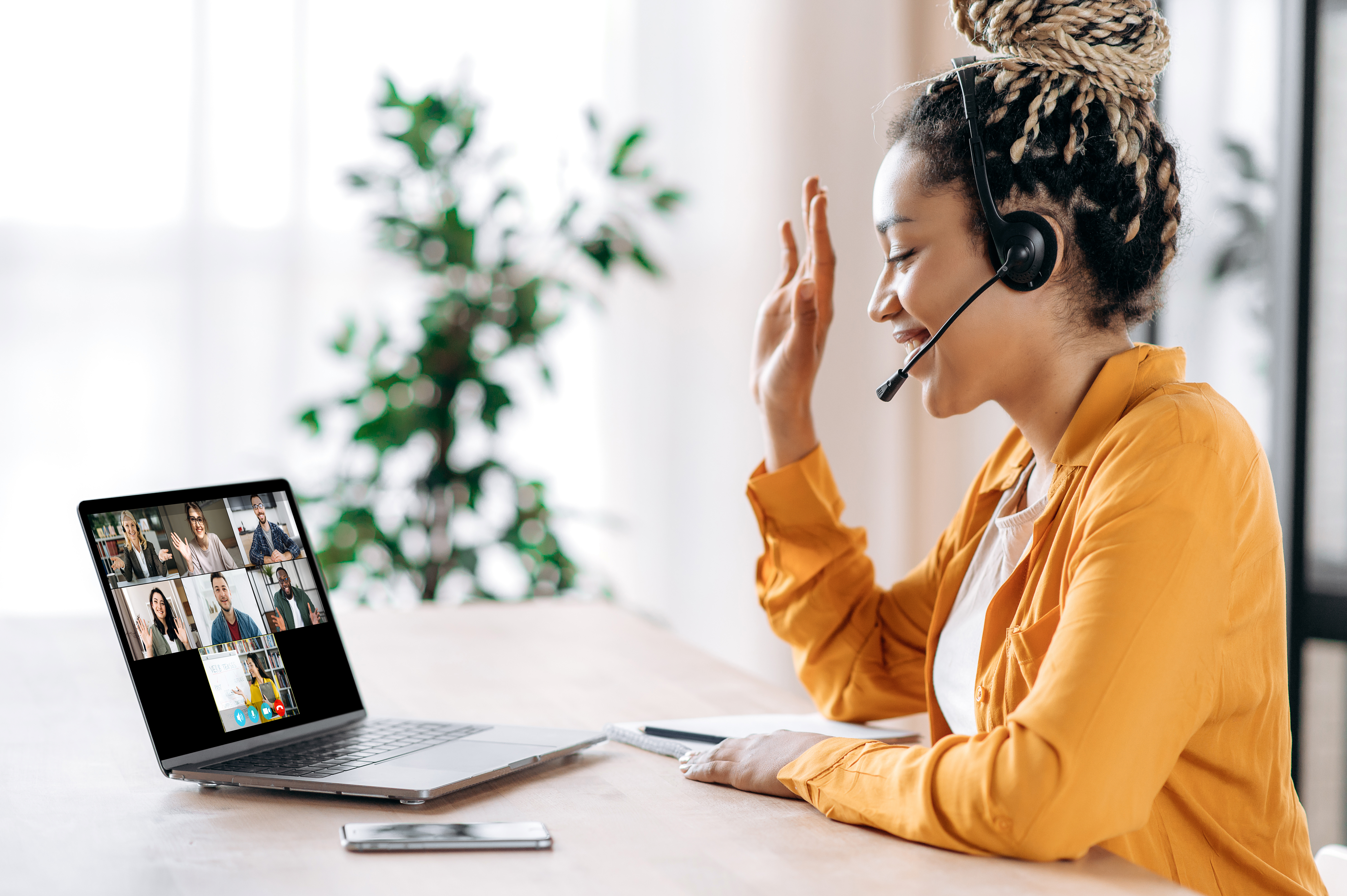 Junge Frau schaut auf Laptop, Hand erhoben, Webinarsituation